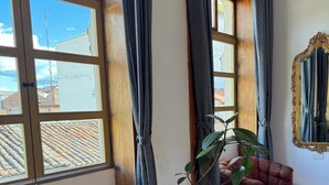 A room with a large window, a potted plant, two upholstered chairs, and a mirror on the wall. - Fantastic Restored Patrimonial Suite (Cuenca)