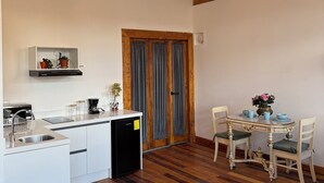 A modern kitchen with a built-in dishwasher, a dining area with a wooden table and chairs, and a decorative chandelier. - Fantastic Restored Patrimonial Suite (Cuenca)