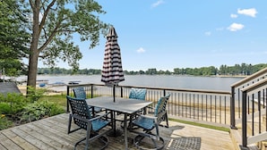 A deck with a table and chairs, overlooking a lake. - Charming 3-bedroom cottage in Coral with WiFi and AC (Coral)