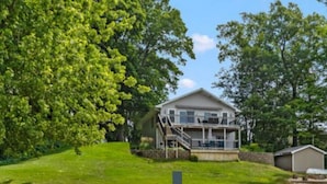 A two-story house with a balcony, a wooden deck, and a small shed. - Charming 3-bedroom cottage in Coral with WiFi and AC (Coral)