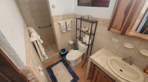 Un baño pequeño con inodoro, lavamanos y un estante con artículos de tocador.