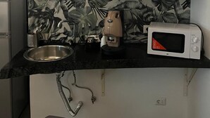 A compact kitchen with a sink, a coffee maker, a microwave, and a cabinet above the counter. - Becial house (Napoli)