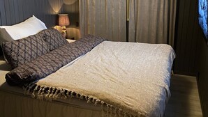 Une chambre à coucher avec un lit, des oreillers, une lampe et des rideaux.