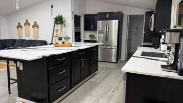 A modern kitchen with black cabinetry, a stainless steel refrigerator, and a white countertop.