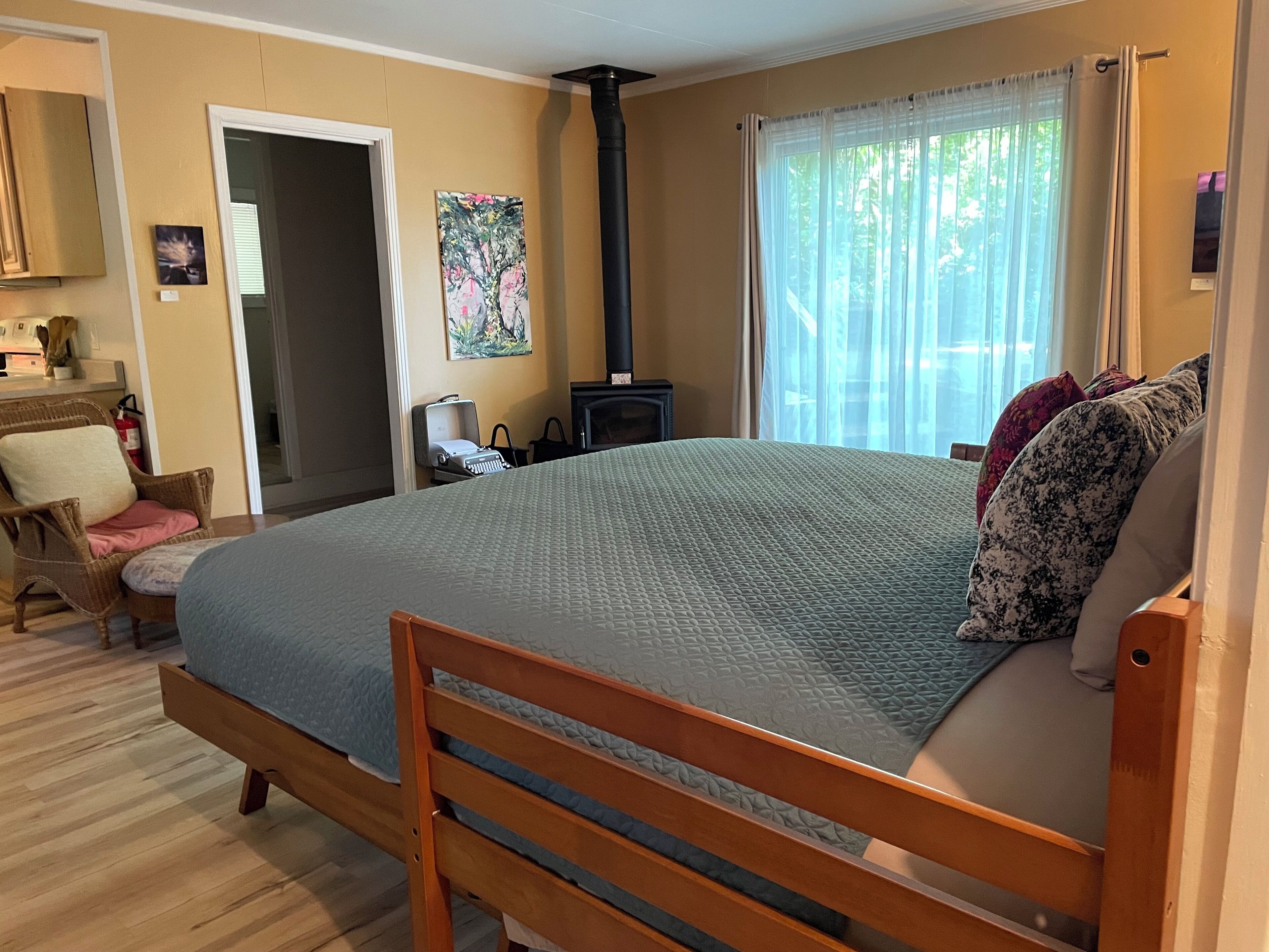 Un dormitorio con cama, una silla, chimenea y ventana con cortinas.
