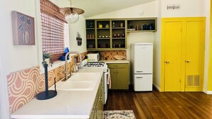 A kitchen with a sink, stove, and a yellow door. - Charming 2-bedroom bungalow in welcoming Austin with WiFi, AC (Austin)