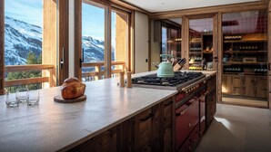 Una cocina con una isla grande, vistas a montañas y una estantería para vinos.