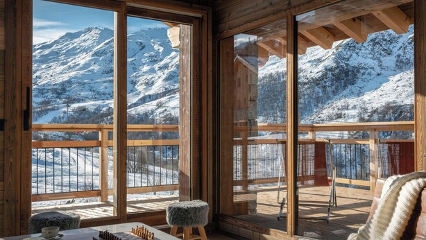 Una habitación acogedora con amplias ventanas que ofrecen vistas a una montaña nevada.
