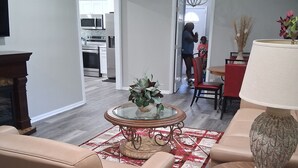A living room with a beige sofa, a glass coffee table with a plant, a wooden side table with a lamp, and a red and white patterned rug. - ABM Southern Vacation Rental 
3-bedroom house in marvelous Savannah with WiFi (Savannah)
