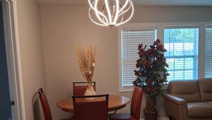 A dining area with a wooden table and chairs, a vase with dried plants, and a modern pendant light. - ABM Southern Vacation Rental 
3-bedroom house in marvelous Savannah with WiFi (Savannah)