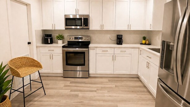 Een moderne keuken met witte kasten, roestvrijstalen apparatuur en een houten vloer.