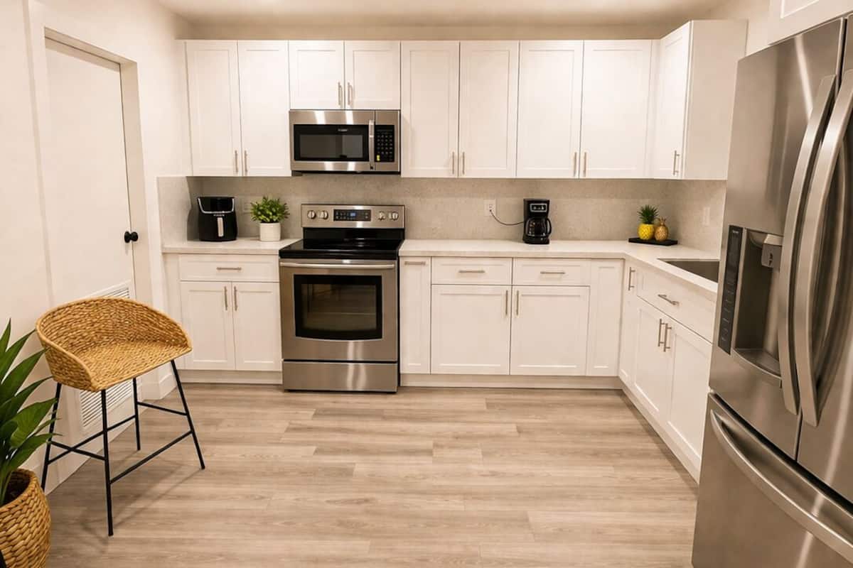 Une cuisine moderne avec des armoires blanches, des appareils en acier inoxydable et un plancher en bois.