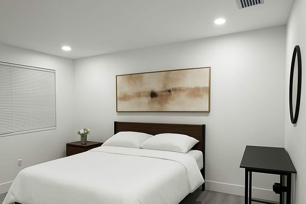 Une chambre à coucher avec un lit, une table de chevet et une œuvre d’art accrochée au mur.