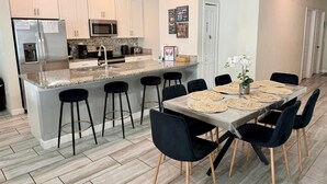 Una cocina moderna con armarios blancos, electrodomésticos de acero inoxidable y encimera de granito.