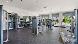 Un gimnasio moderno con diversos equipos de ejercicio, amplias ventanas y vistas al exterior.