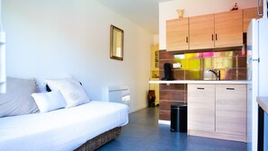 A compact room with a bed, kitchenette, and a small bathroom. - Studio for 3 people – Shared pool (Les Sables-d´Olonne)