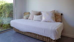 A bed with a white bedspread and multiple pillows, positioned against a wall with a large window overlooking greenery. - Studio for 3 people – Shared pool (Les Sables-d´Olonne)