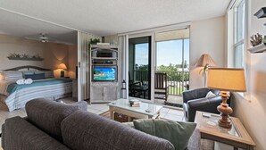 A modern bedroom with a bed, TV, and a balcony with a view.