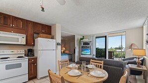 A compact kitchen with modern appliances, a dining area with a round table, and a balcony with a view.