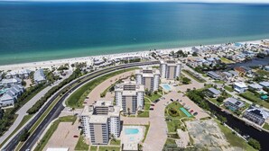 An aerial view of a coastal residential area with high-rise buildings, a beach, and a marina.