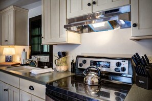 Una cocina con estufa de acero inoxidable, hervidor y bloque de cuchillos.