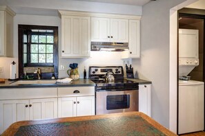 A kitchen with white cabinets, a stove, and a sink. - Storybook Cottage with Fireplace (Banner Elk)