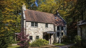 A stone house with a sloped roof, a front porch, and a well-maintained garden. - Storybook Cottage with Fireplace (Banner Elk)