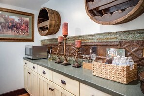 A kitchen with a vintage microwave, a wooden barrel, a candle holder, and a wicker basket with water bottles.