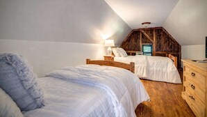 A bedroom with two beds, wooden furniture, and a sloped ceiling. - Storybook Cottage with Fireplace (Banner Elk)
