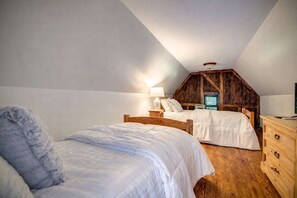 A bedroom with two beds, wooden furniture, and a sloped ceiling. - Storybook Cottage with Fireplace (Banner Elk)