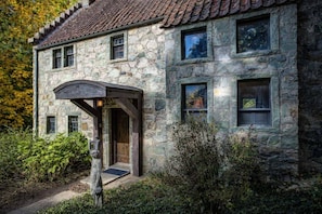 Ein Steinhaus mit Ziegeldach, überdachter Veranda und kleiner Veranda.