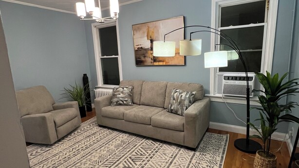 A living room with a beige sofa, patterned rug, and a floor lamp. - Cozy house (Jersey City)