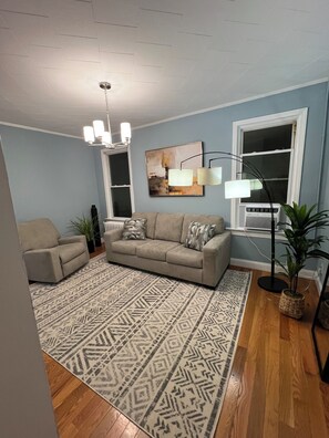 A living room with a beige sofa, patterned rug, and a floor lamp.