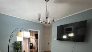 A living room with a sofa, patterned rug, and a TV mounted on the wall. - Cozy house (Jersey City)