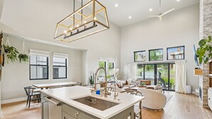 Une cuisine spacieuse dotée d’un îlot central, de grandes fenêtres et d’un ventilateur de plafond moderne.