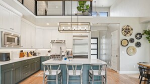 Une cuisine moderne dotée d’un îlot central, d’appareils électroménagers en acier inoxydable et d’une mezzanine.