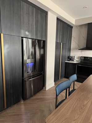 A modern kitchen with dark wood cabinets, stainless steel appliances, and a herringbone wood floor. - Wyndham Vacation Resort Downtown ATL walking distance to MercedesBenz Stadium (Atlanta)