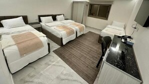 A hotel room with two beds, a desk, a chair, an air conditioning unit, and a window. - Mountain Echo Inn (At-Taybeh)