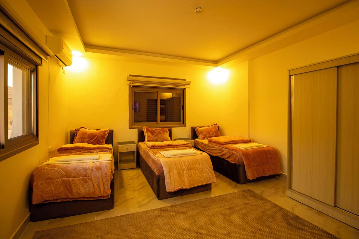 A hotel room with four single beds, a large mirror, and a wardrobe.