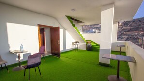 A modern interior with a green artificial grass floor, a wooden door, a staircase with green steps, and a view of a hillside. - Mountain Echo Inn (At-Taybeh)