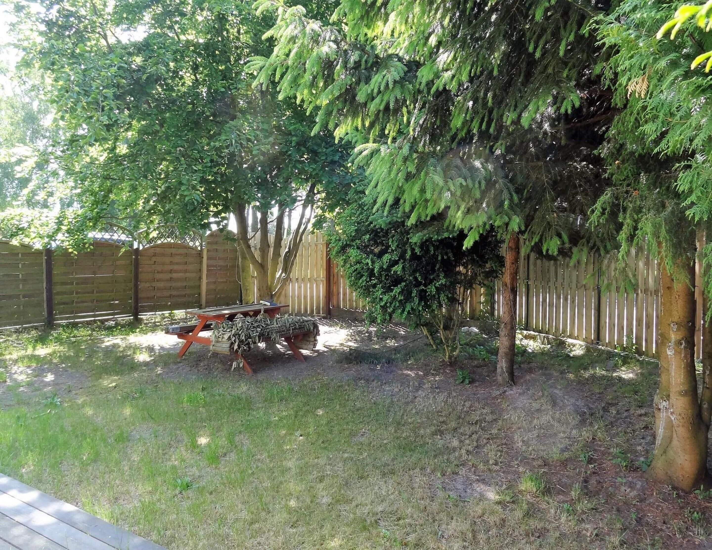 A backyard with a wooden deck, a small tree, and a fence.