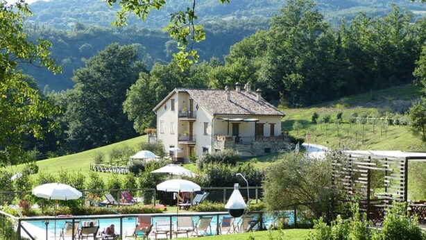 A two-story house with a balcony, surrounded by lush greenery and a swimming pool area with lounge chairs and umbrellas. - Holiday Resort in Villanova D'albenga (Villanova d'Albenga)
