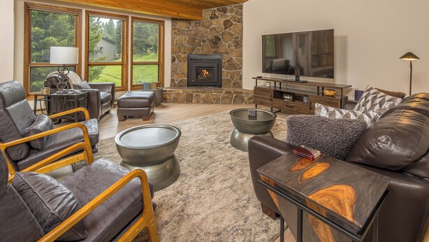 A cozy living room with a stone fireplace, leather sofas, and a flat-screen TV.