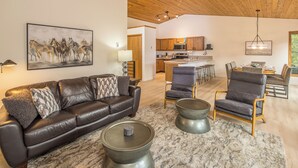 A living room with a leather sofa, two metal coffee tables, and a painting of horses.