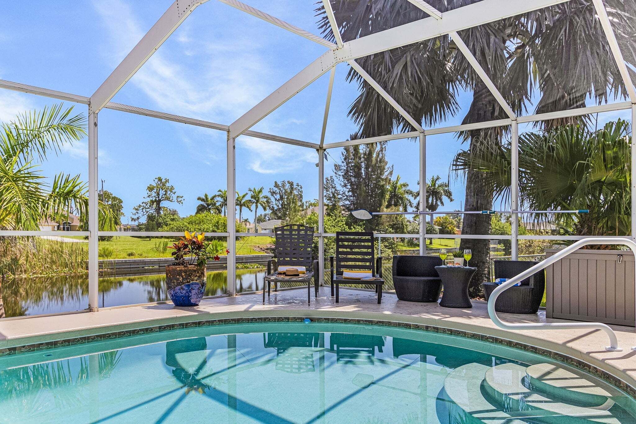 Un área de piscina con terraza cubierta, sillas y vistas al paisaje circundante.
