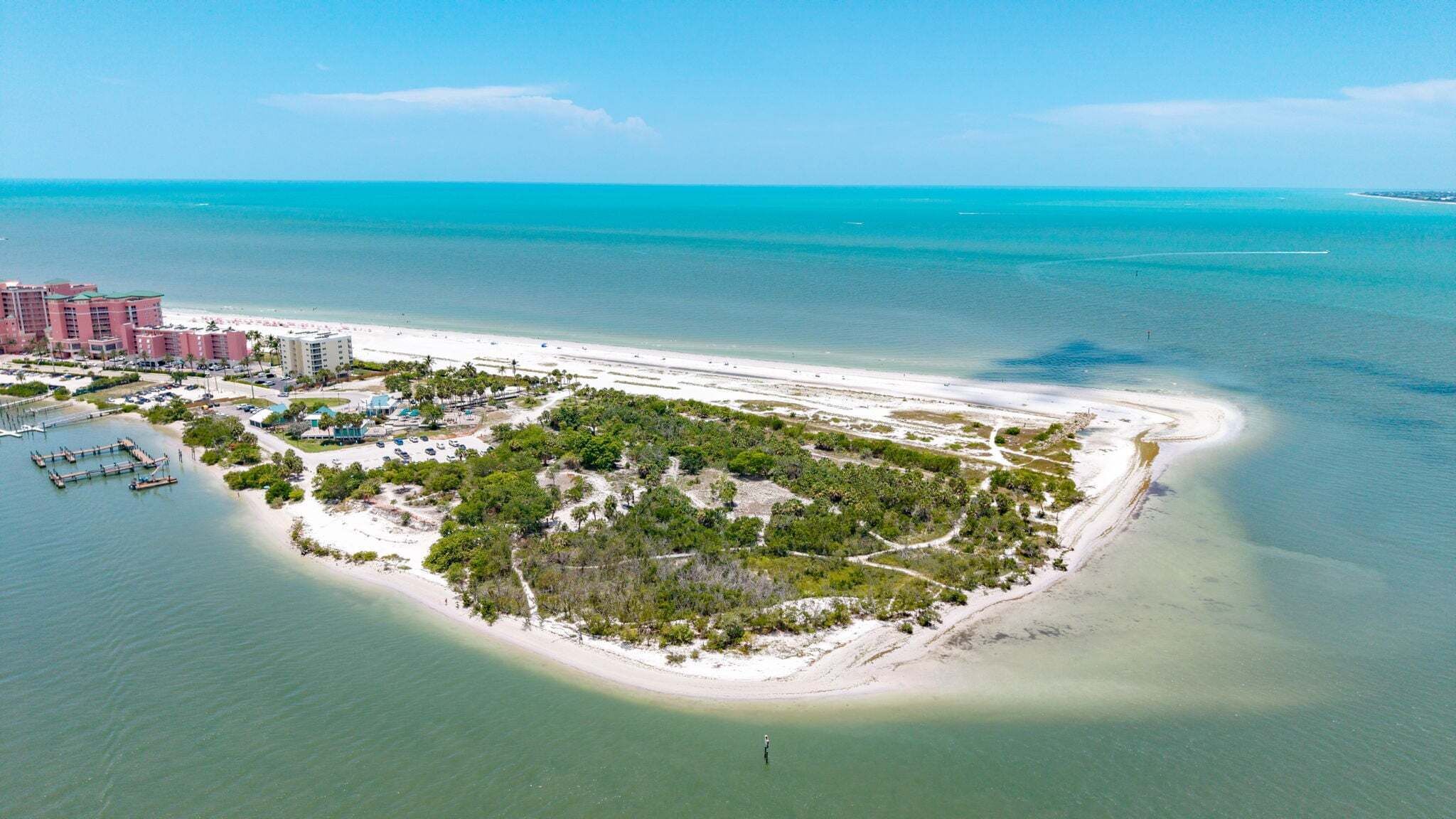 Vue aérienne d’une station balnéaire avec une plage de sable, un port de plaisance et un ensemble dense de bâtiments.