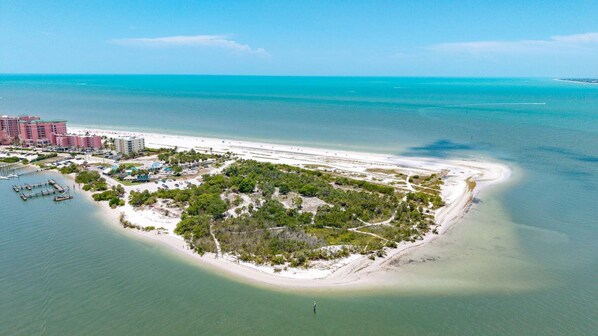 An aerial view of a coastal resort with a sandy beach, a marina, and a dense cluster of buildings.