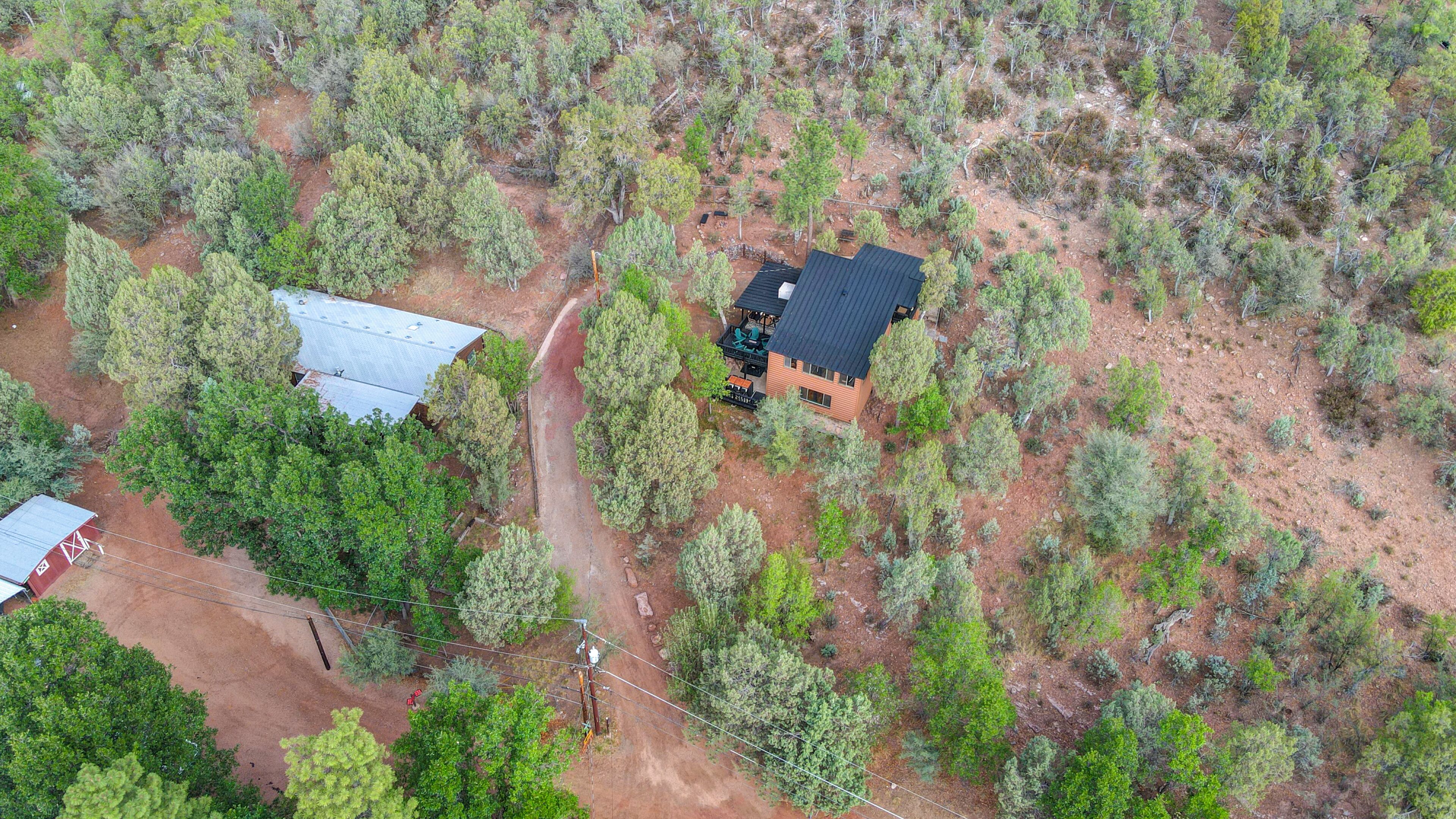 An aerial view of a property with a house, a fenced area, and a dirt road.