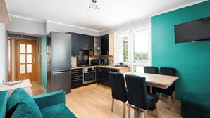 Une cuisine moderne avec un coin repas, un mur de couleur turquoise et un téléviseur à écran plat.