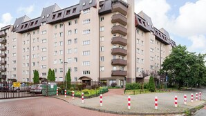 A multi-story residential building with balconies, a gated entrance, and a landscaped area with trees and shrubs. - Wrzeciono Comfortline Apartment (Warszawa)